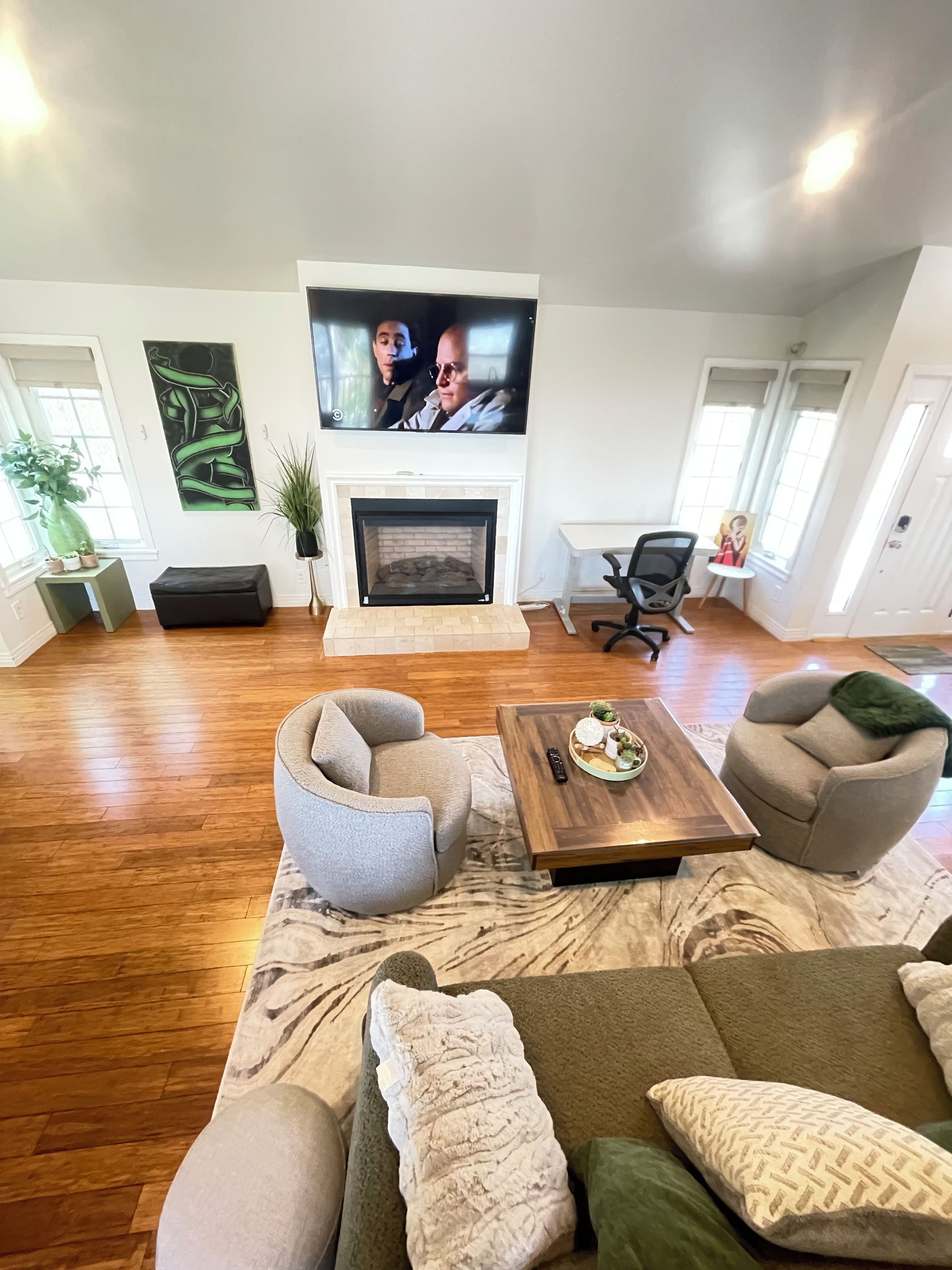 A spacious living room with a fireplace, comfortable seating, and a television mounted above it.