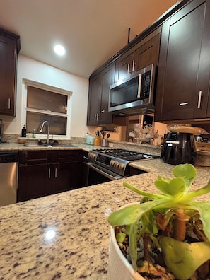 A kitchen with dark wooden cabinets, a stainless steel microwave, a gas stove, and a sink.