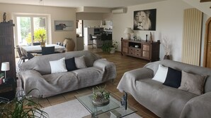A spacious living room with two grey sofas, a glass coffee table, and a dining area with a table and chairs. - Magnificent, peaceful villa surrounded by olive trees. Exceptional panoramic view (Fayence)