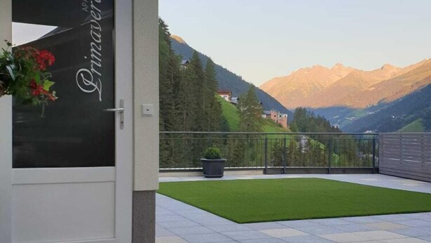 A hotel entrance with a glass door, a small lawn, and a mountain view. - Apartment in See near Ski Slopes (See)