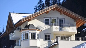 A multi-story house with a balcony, large windows, and a snowy landscape. - Apartment in See near Ski Slopes (See)