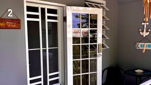 A room with a large sliding glass door, a small table with a chair, and a sign indicating room number 2. - Beautiful, spacious house 9 minute drive to beach with electric generator (Rincón)