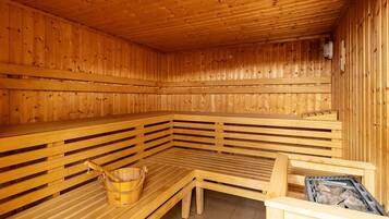 Eine Holzsauna mit Bänken und einem Holzeimer.