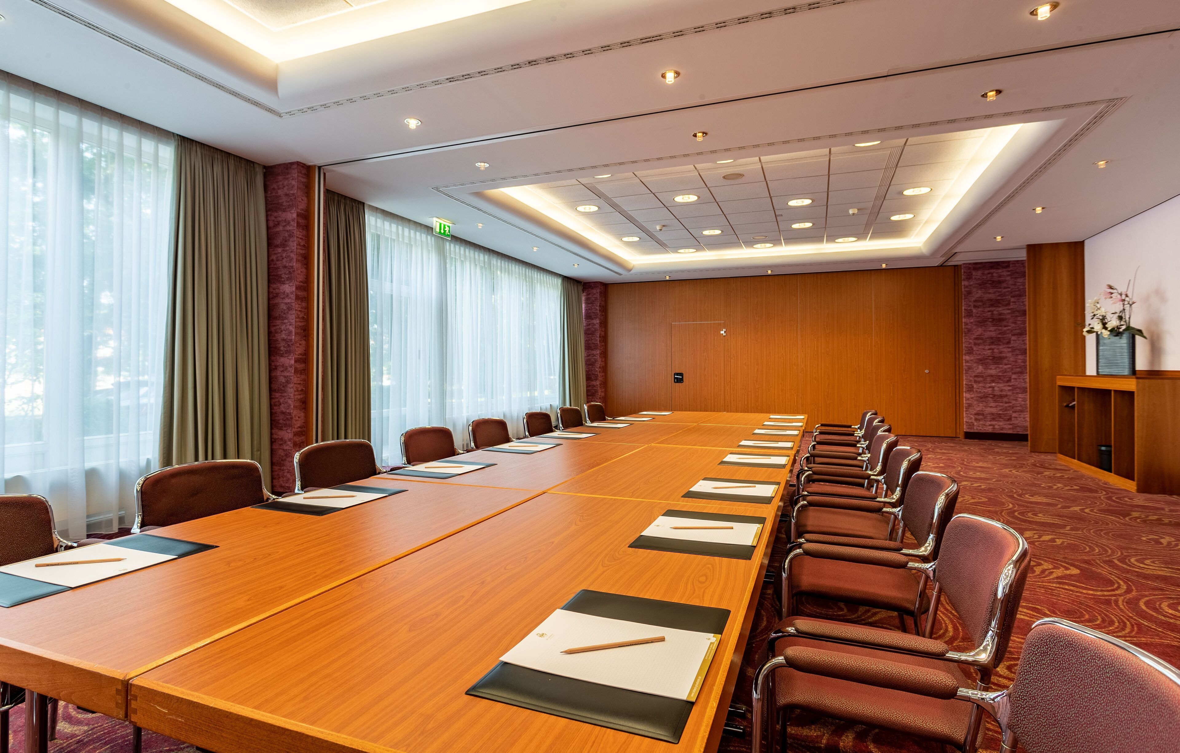 Une salle de conférence avec une longue table, des chaises et un mur recouvert de panneaux en bois.