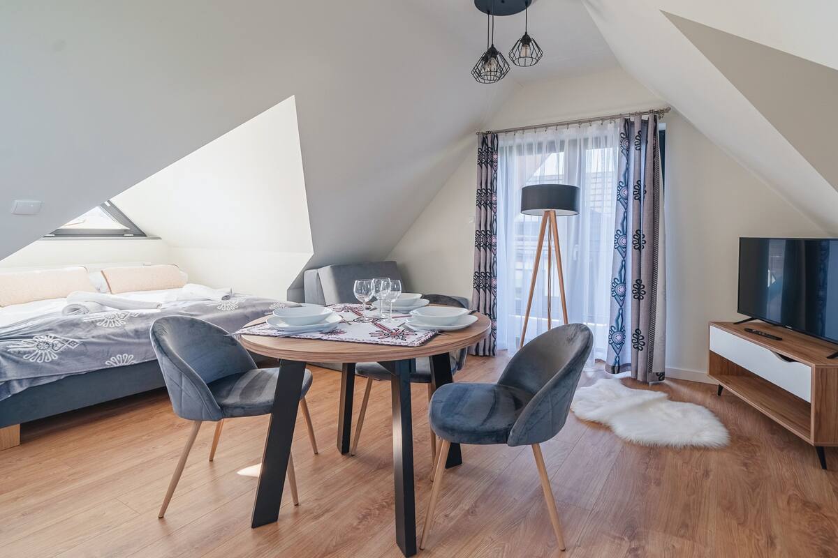 Et moderne, veloplyst værelse med spiseplads, seng og fjernsyn.