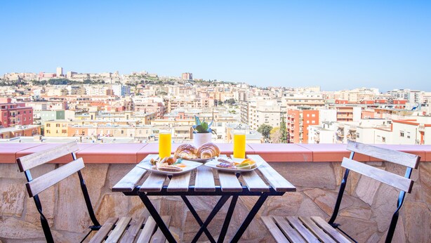 A balcony with a table set for breakfast, overlooking a cityscape. - Cagliari Upper House (Cagliari)
