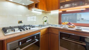 A modern kitchen with stainless steel appliances, wooden cabinets, and a window overlooking the city. - Cagliari Upper House (Cagliari)
