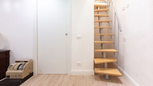 Eine Treppe mit Holzstufen und einem Metallgeländer, die zu einem Zwischenpodest mit einer weißen Tür führt.