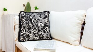 Ein weißes Sofa mit einem gemusterten Kissen und einem Buch darauf.