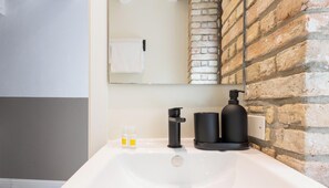 A bathroom with a white sink, black soap dispenser, and a mirror above it. - Maison Garibaldi - Camera Matrimoniale n.3 (Cagliari)