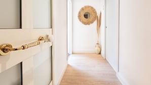 A hallway with a wooden floor, a decorative mirror, and a vase with tall grasses. - Maison Garibaldi - Camera Matrimoniale n.1 (Cagliari)