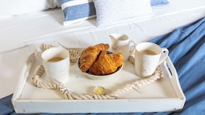 A tray with croissants, coffee cups, and a jug on a bed with blue bedding. - Maison Garibaldi - Camera Matrimoniale n.1 (Cagliari)