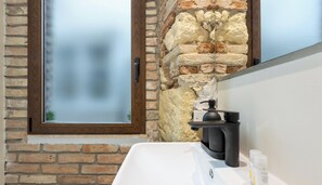Ein Badezimmer mit einem weißen Waschbecken, einem schwarzen Wasserhahn und einem Spiegel.