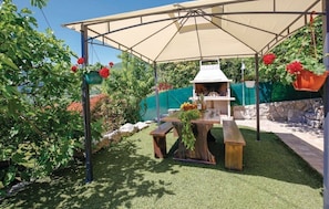 Relax in a serene outdoor space with a grill station, comfortable benches, and lush greenery.