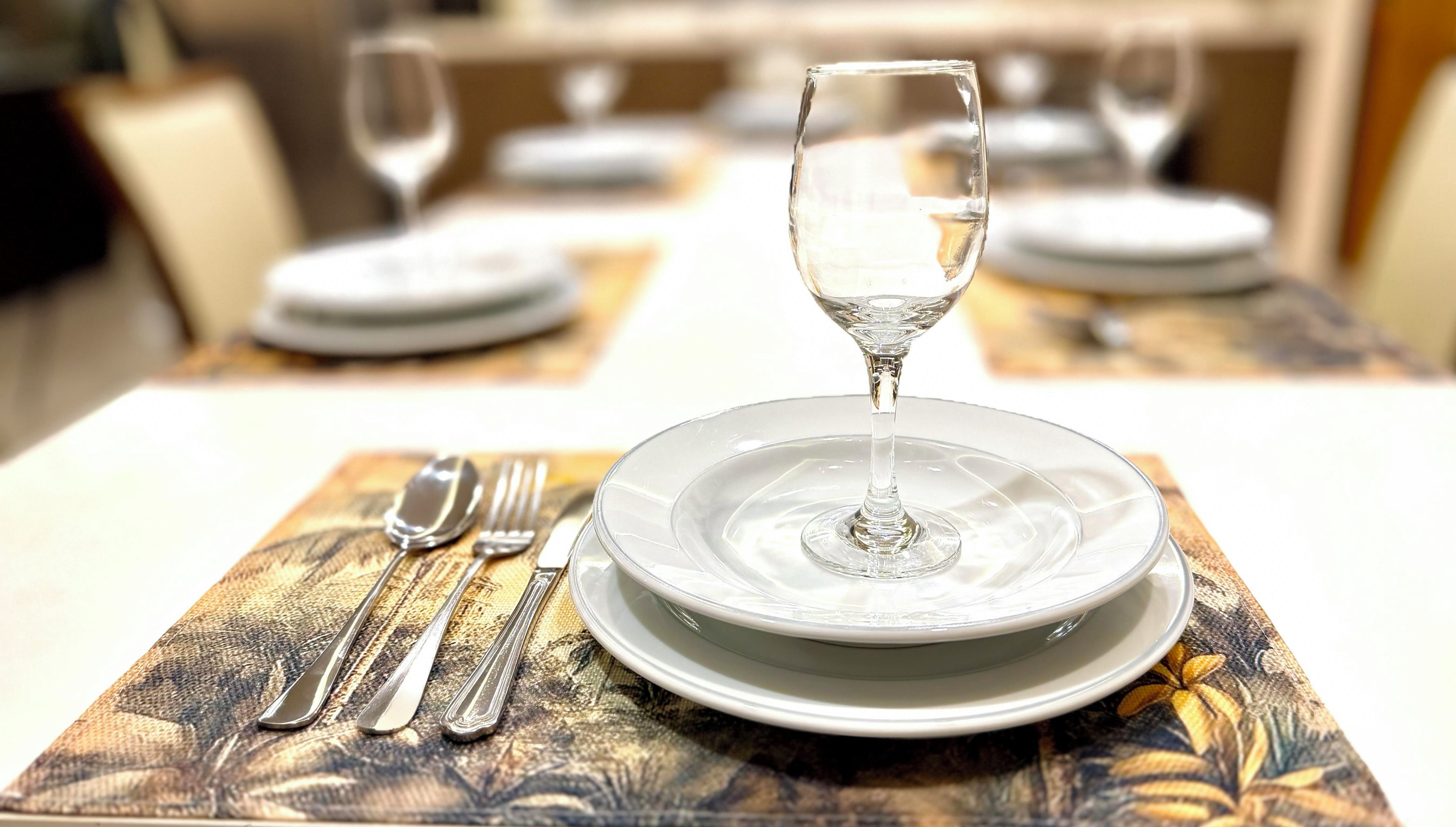 A dining table set with a plate, a glass, and cutlery.
