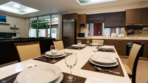 Un comedor moderno con una larga mesa dispuesta para cuatro personas, con platos, vasos y cubiertos.
