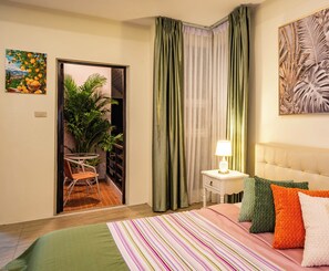 Ein Hotelzimmer mit einem Bett, einem Nachttisch mit Lampe, einem Sessel, einer Zimmerpflanze und einem Gemälde an der Wand.