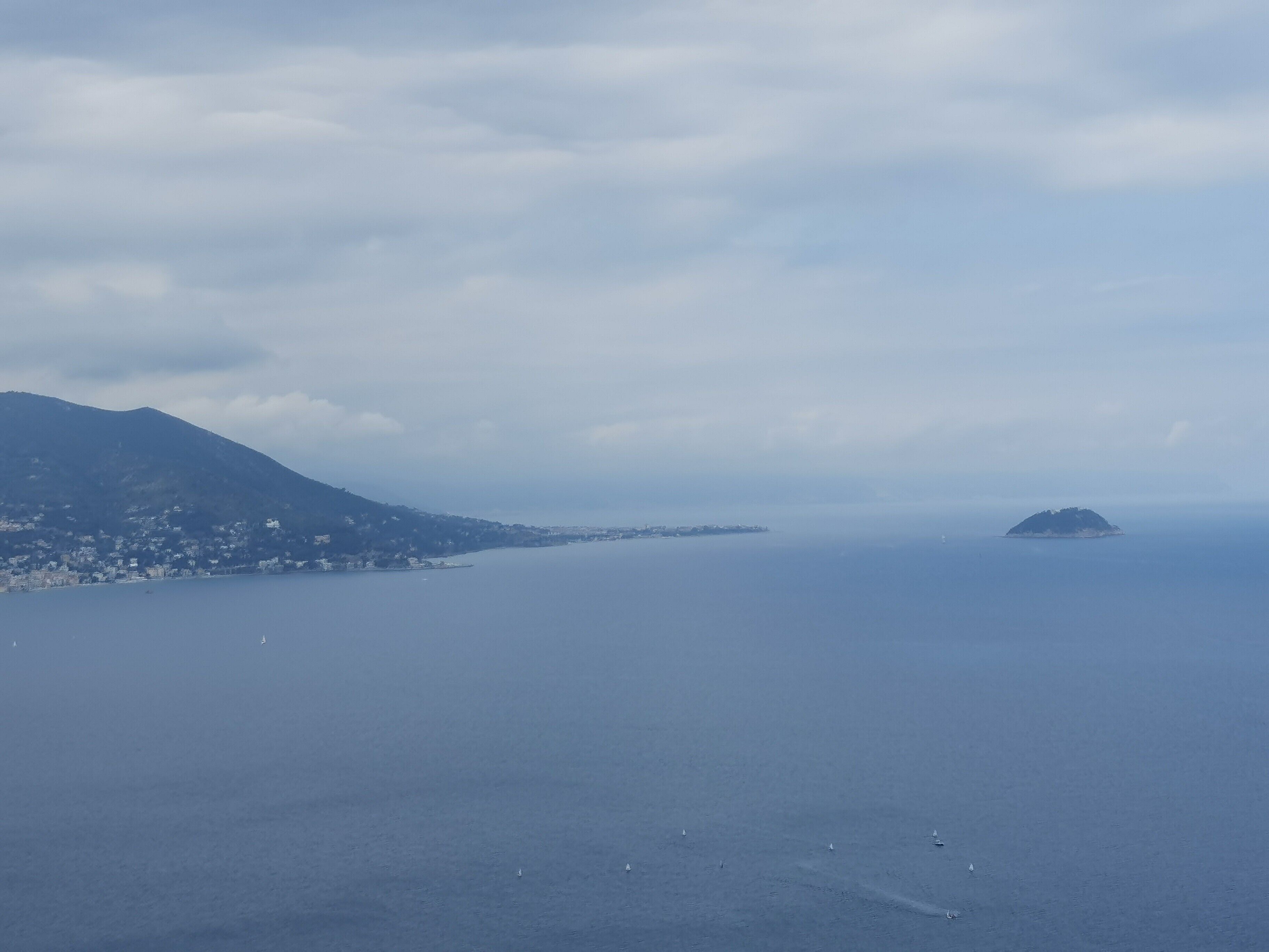 Eine Küstenlandschaft mit einem Berg, einer kleinen Insel und ruhigem Meer.