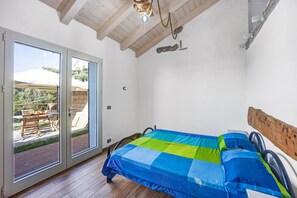 A bedroom with a bed, a wooden headboard, a ceiling fan, and a sliding glass door leading to an outdoor patio.
