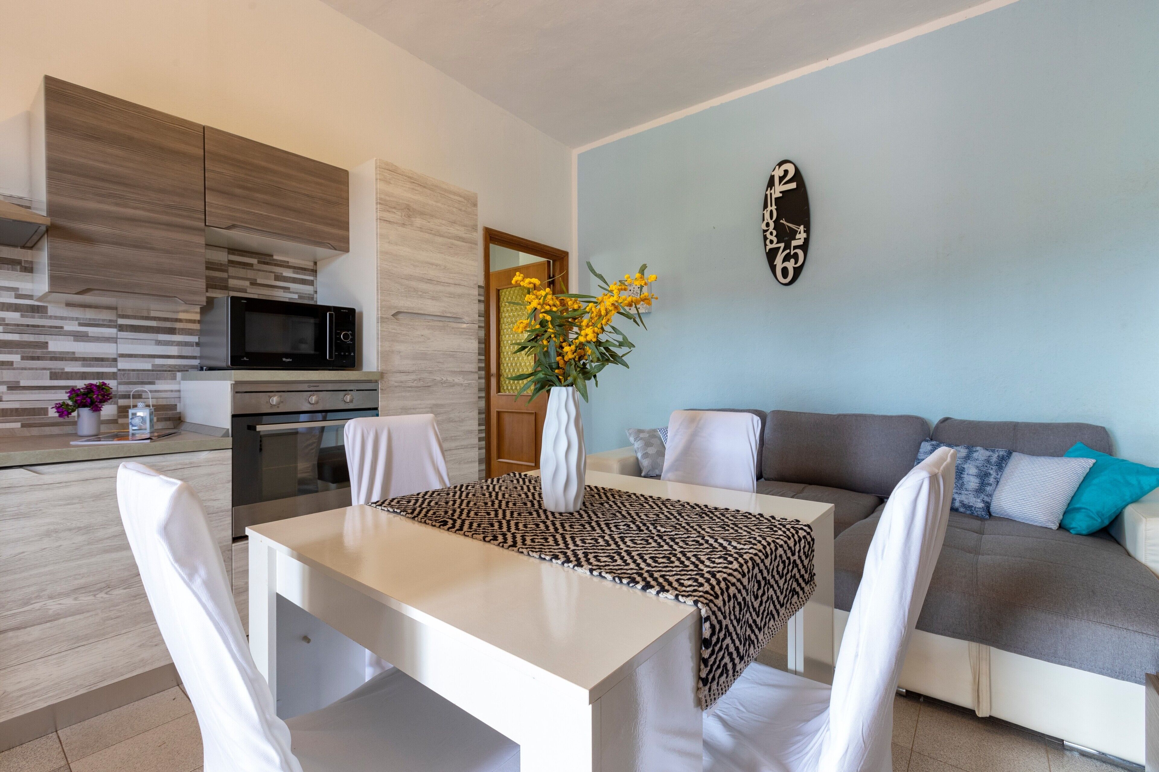 Una cucina moderna con forno a microonde, forno e zona pranzo con tavolo e sedie.