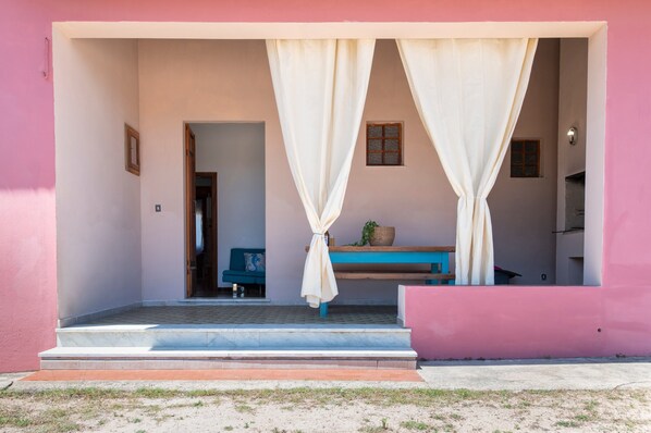 Un bâtiment à la façade rose, avec un canapé bleu et des rideaux blancs.