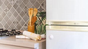 A kitchen with a gas stove, wooden utensils, a rolled-up towel, and a white appliance.