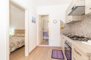 A compact kitchen with a gas stove, wooden cabinets, and a tiled backsplash.