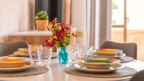 A dining table set with plates, glasses, and a vase of flowers. - Apartment 'Endless Summer' with Sea View, A/C and Balcony (Isola Rossa)