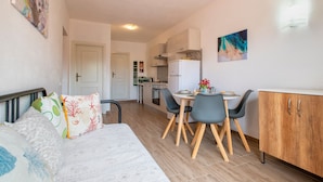 A compact living space with a bed, a dining table with chairs, a kitchenette, and a small cabinet. - Apartment 'Endless Summer' with Sea View, A/C and Balcony (Isola Rossa)