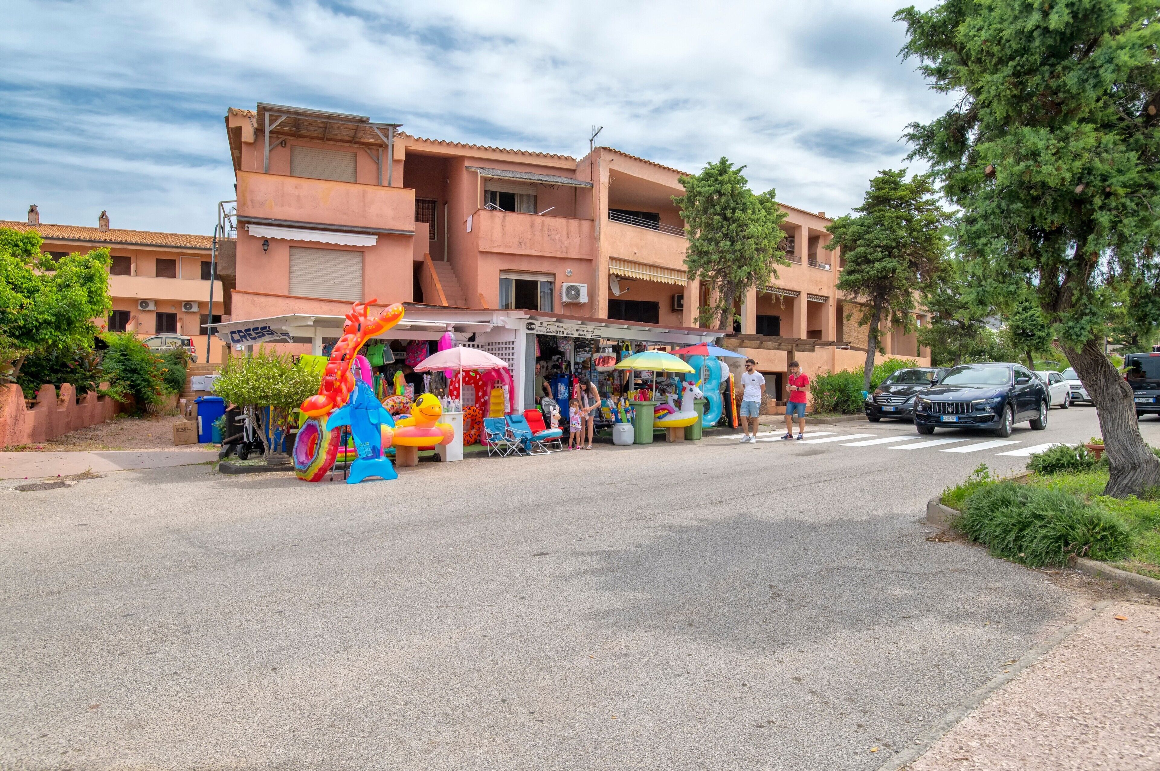 Una calle con una fila de juguetes inflables de colores y un edificio con balcones.