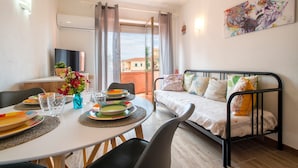 A room with a bed, dining table, chairs, and a TV. - Apartment 'Endless Summer' with Sea View, A/C and Balcony (Isola Rossa)