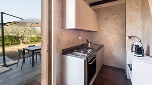 Une cuisine de taille réduite, équipée d’une cuisinière à gaz, d’un four et de meubles blancs.