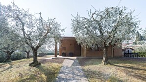 Un bâtiment avec un chemin de pierre menant à une porte, entouré d’oliviers.