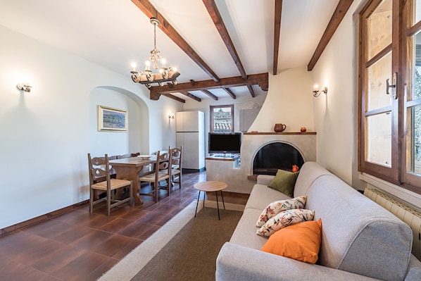 A living room with a fireplace, a sofa, a dining table with chairs, and a television.
