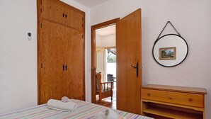 Een slaapkamer met een bed, een houten garderobe, een houten dressoir en een deur die uitkomt op een balkon.
