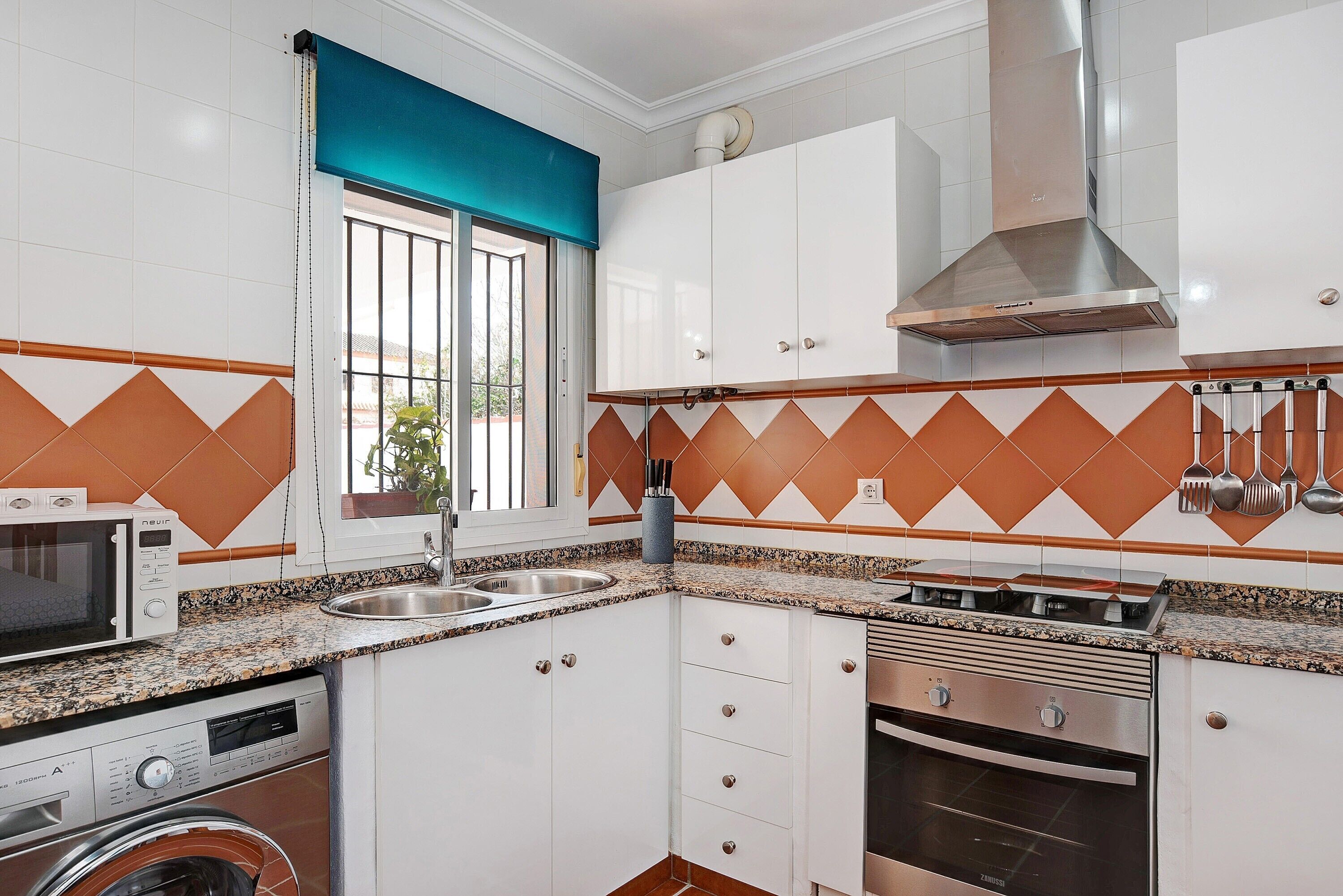 A kitchen with white cabinets, a microwave, a stove, and a washing machine.