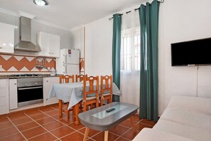 Une cuisine compacte équipée d’une cuisinière, d’un four et d’un coin repas avec des chaises et une table.