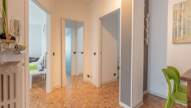 A hallway with a tiled floor, white walls, and a green chair. There are doors leading to other rooms. - EARTH -  WHOLE APARTMENT 5 GUESTS (Biandrate)
