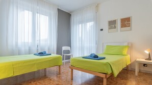 A room with two beds, a chair, and a nightstand with a lamp. - EARTH -  WHOLE APARTMENT 5 GUESTS (Biandrate)