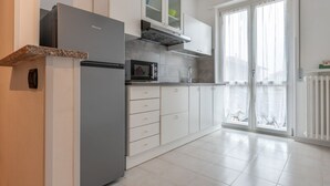 A modern kitchen with a built-in refrigerator, microwave, and oven, white cabinets, and a sliding glass door to the balcony. - EARTH -  WHOLE APARTMENT 5 GUESTS (Biandrate)