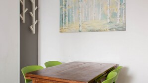 A small wooden table with a drawer, surrounded by four green chairs, against a white wall with a painting of a forest. - EARTH -  WHOLE APARTMENT 5 GUESTS (Biandrate)