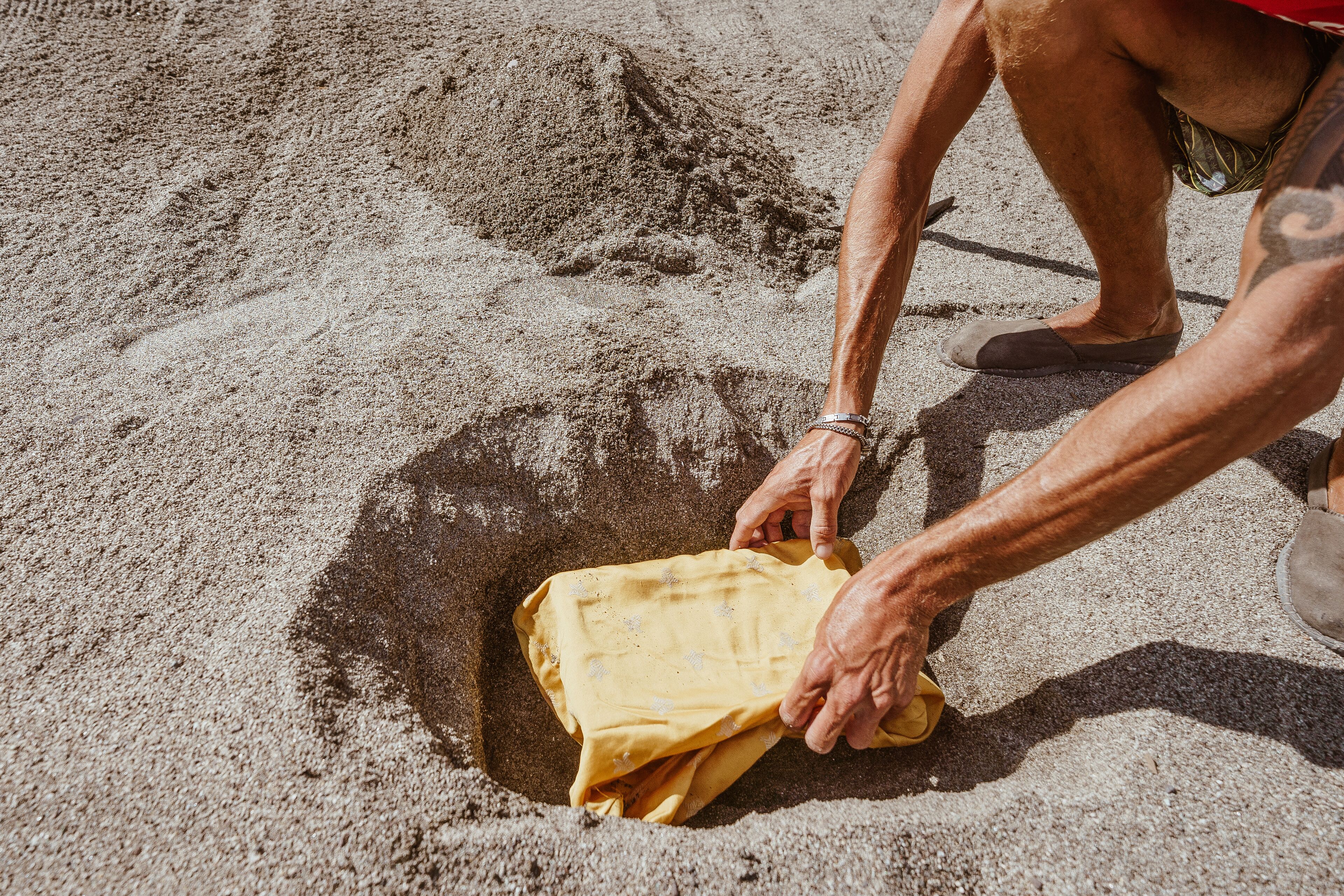 A person digging a hole in the sand.