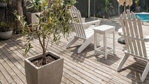 A wooden deck with Adirondack chairs, a small table, and a potted plant. - Pet Friendly - Preston Alfresco Poolside Retreat Rye (Rye)