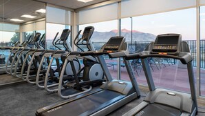 A row of treadmills in a gym with large windows offering a view of mountains. - Fairfield Inn & Suites by Marriott Winnemucca (Winnemucca)