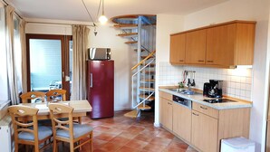 Una cocina compacta con armarios de madera, lavavajillas integrado y comedor con mesa y sillas.