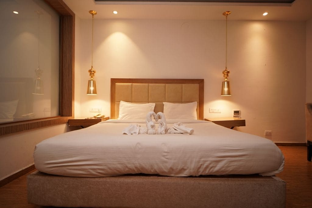 Ein Hotelzimmer mit einem großen Bett, zwei Nachttischen, einem Spiegel und Pendelleuchten.