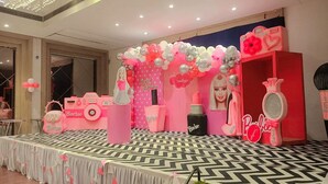 A Barbie-themed event space with a stage, balloons, and various Barbie-themed decorations. - Hotel Amora (Rajnandgaon)