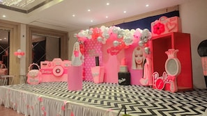 Un espace événementiel sur le thème de Barbie, avec une scène, des ballons et diverses décorations inspirées de Barbie.