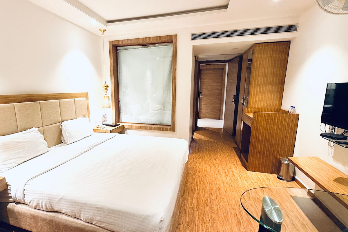A hotel room with a large bed, a television, a desk, and a wardrobe.