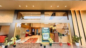 A hotel entrance with a glass facade, a reception desk, and a sign advertising lunch, dinner, and hot tea. - Hotel Amora (Rajnandgaon)